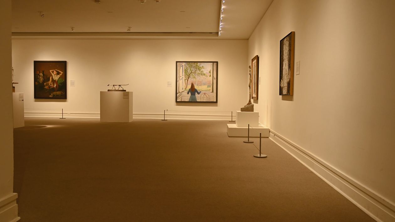 Framed paintings displayed in a softly lit gallery