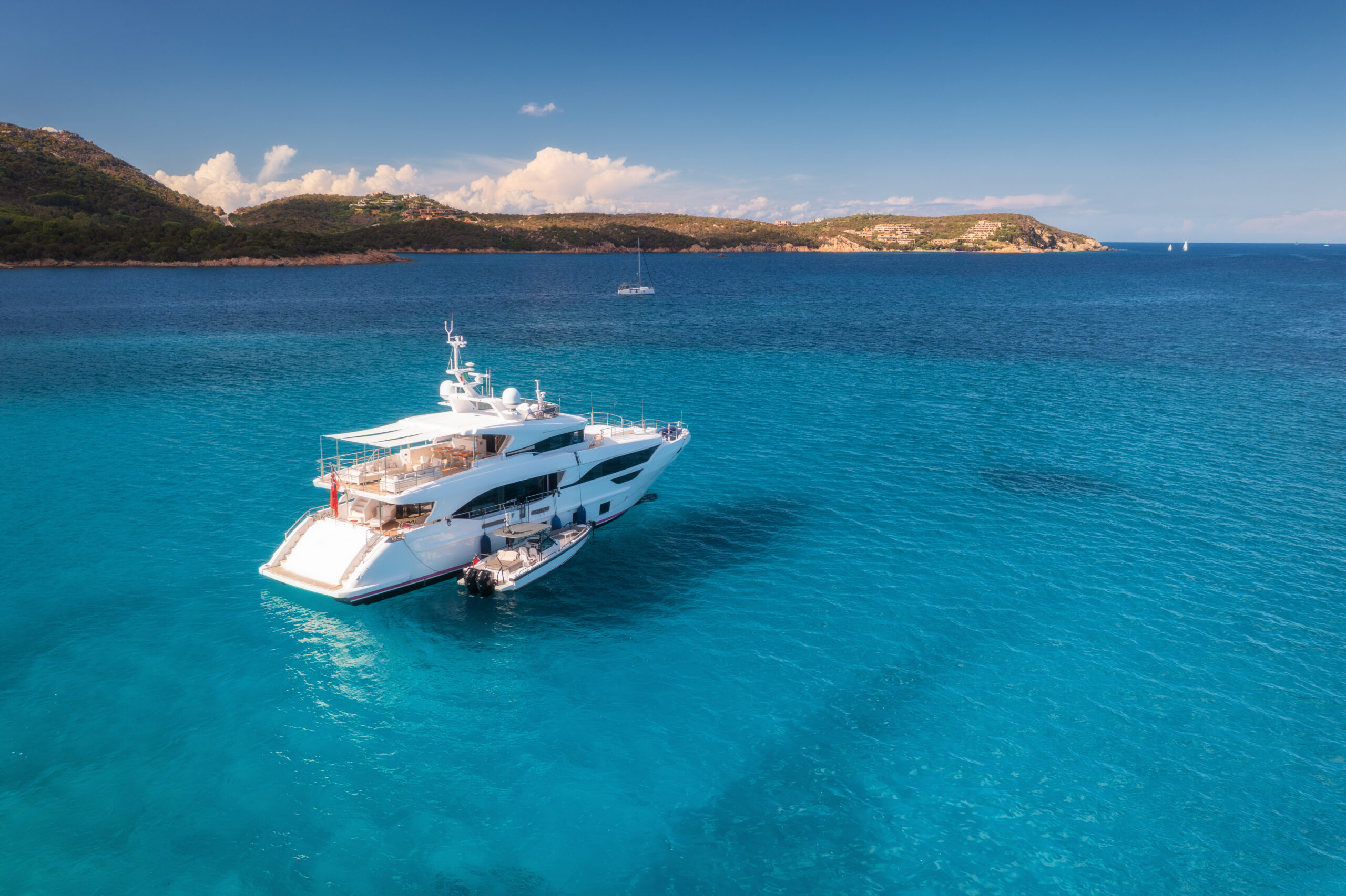 A white yacht at anchor in clear turquoise water